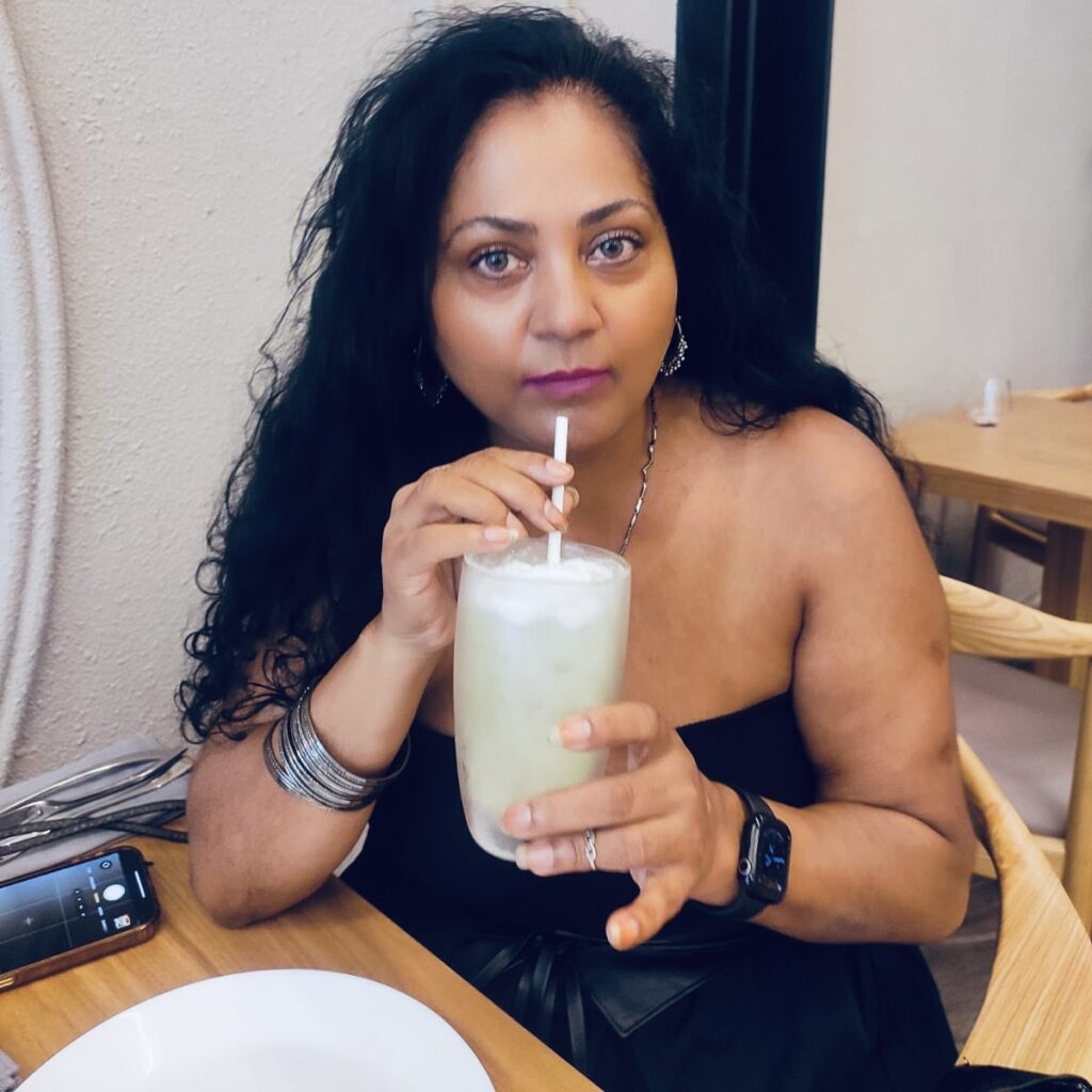 This image is of Fauzia Rizvi, a food influencer sitting at the E-motion cafe in Bangkok sipping a white colored cocktail | www.followfauzia.com